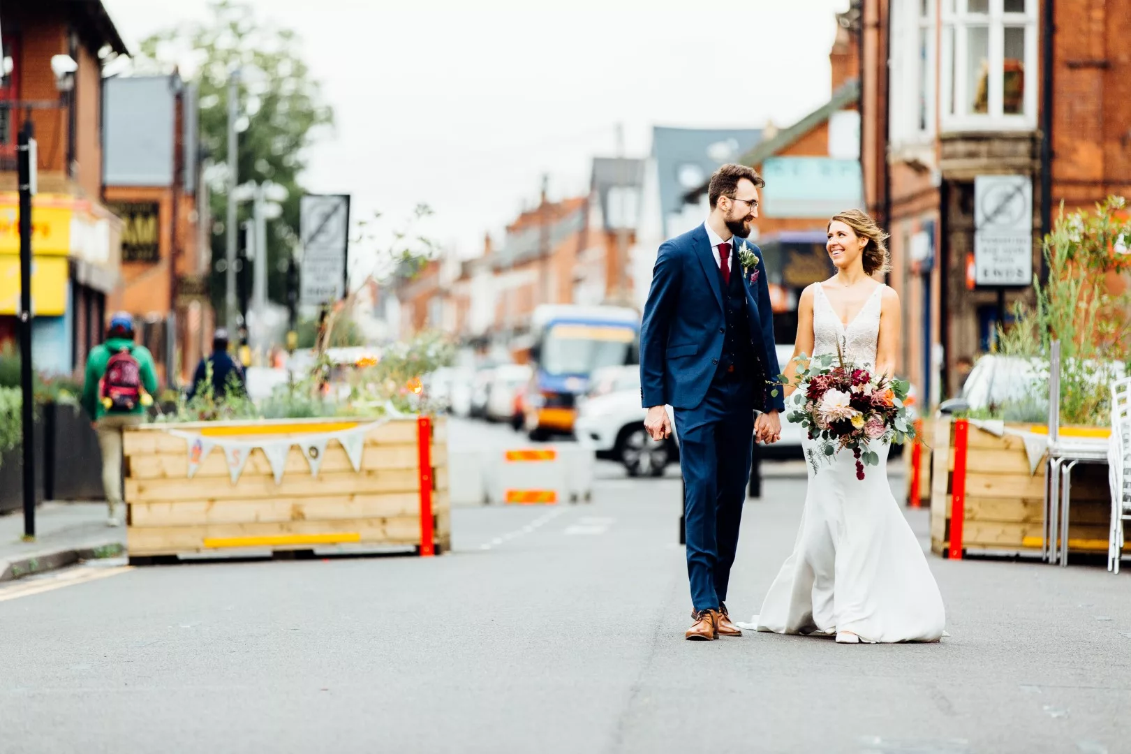 bride holding a bouquet and groom walking down York Road, Kings Heath, Birmingham