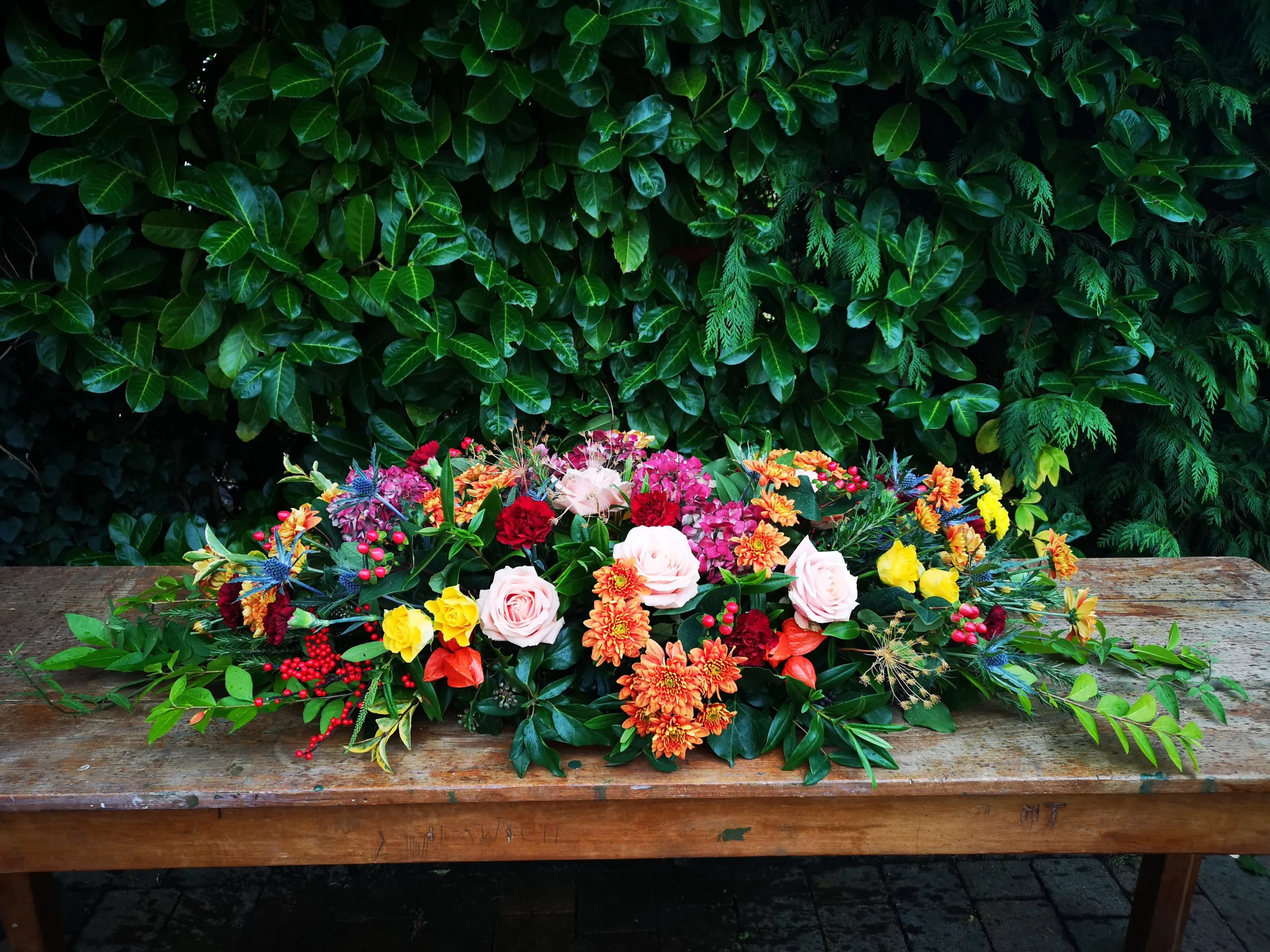 an image of a large autumnal coloured coffin spray on a table